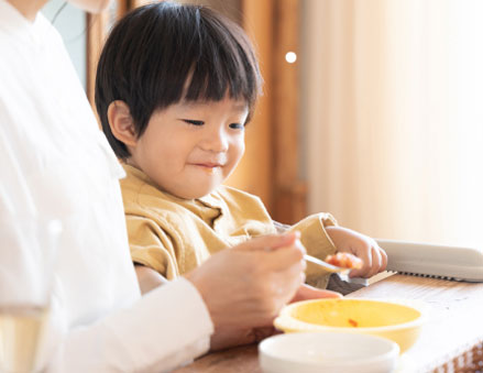 大人と一緒に子供用食器を使って食事をする子ども