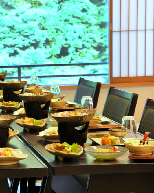 宴会場に並んだテーブルと椅子。テーブル上には様々な食事が準備されている。