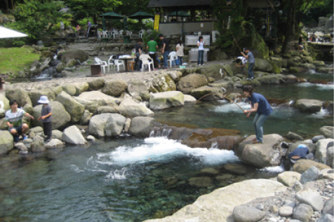 澄んだ流れが特徴的な川辺でマス釣りを楽しむ人