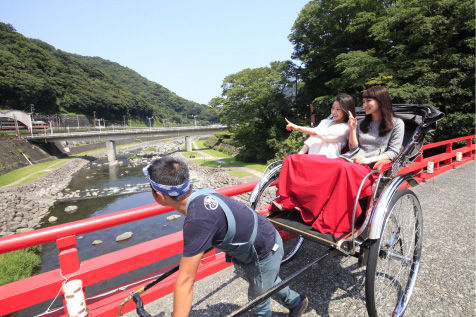 緑豊かな小道を走る赤い車体の人力車