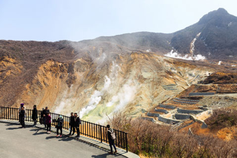 大涌谷の展望台で吹き上がる煙を見る観光客